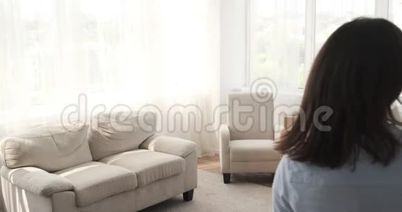 一个女人走进新房子透过窗户看视频的预览图