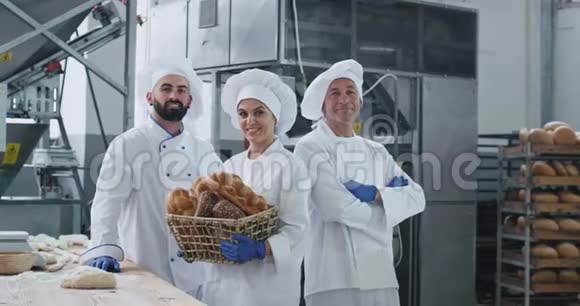商业三个面包师在一个大的面包店里脸上挂着迷人的肖像笑容满面大而直视视频的预览图