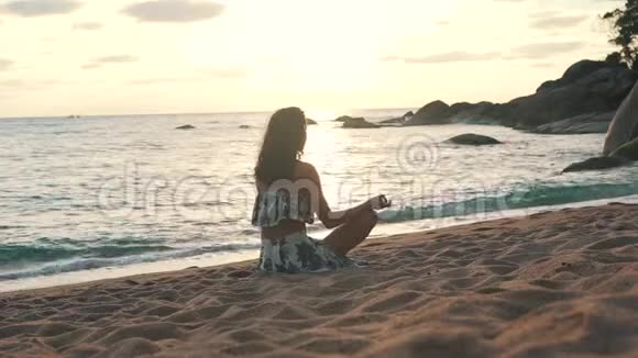 女孩坐在海边的沙滩上沉思视频的预览图