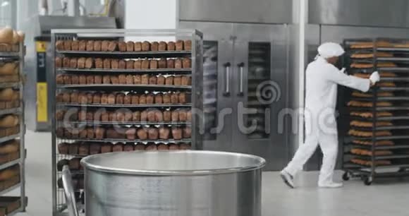 面包行业的面包师穿着特别的制服准备面团加入更多的面粉背景工人移动视频的预览图