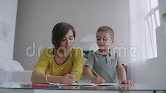妈妈和儿子坐在白色房间的镜子桌前用彩色铅笔画画笑着笑着视频的预览图