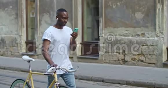 年轻的非洲裔美国人使用智能手机看屏幕推时髦的现代自行车视频的预览图