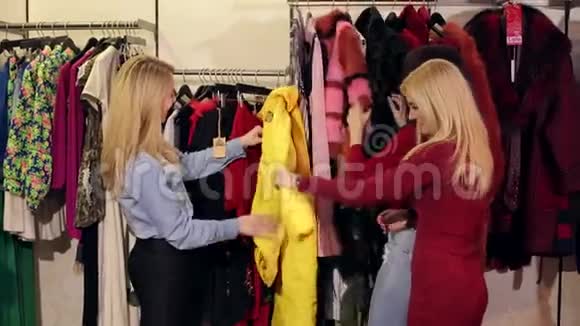 三个时尚女孩在一家服装店看着一件黄褐色的毛皮外套视频的预览图