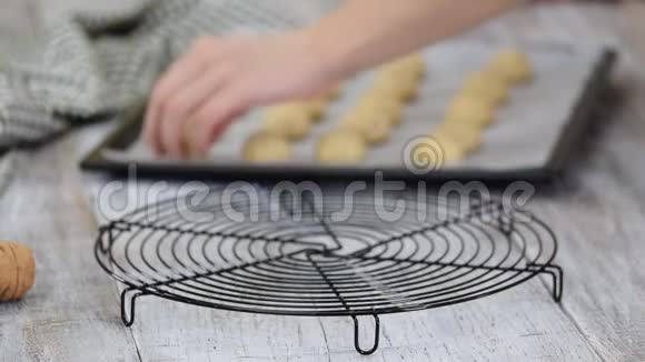 在家做雪球饼干的女人女人的手把饼干放在线架上冷却视频的预览图