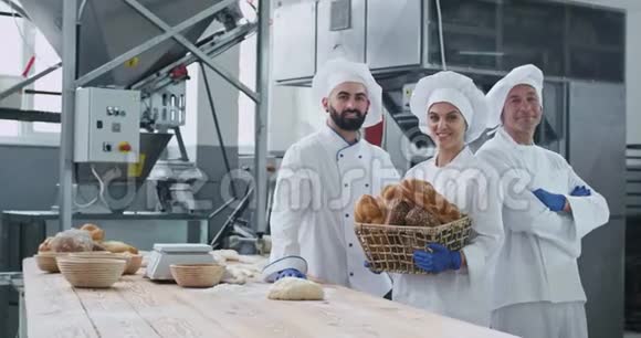 工业面包店的两个男女面包师的画像直视着镜头微笑着的大女人捧着视频的预览图