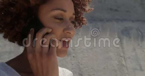 在阳光4k的海滩上年轻的非裔美国妇女在手机上交谈的侧面景色视频的预览图