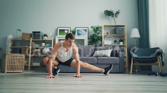 有吸引力的男性运动员在家中进行个人训练时伸展腿部视频的预览图