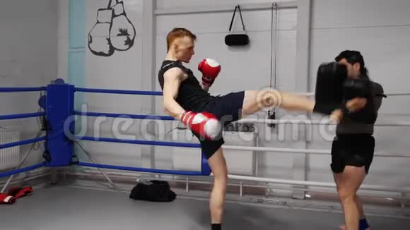 拳击手在搏击俱乐部训练时使用运动垫练习踢腿视频的预览图