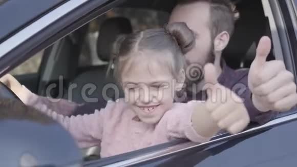 时髦的父亲和漂亮的女儿坐在司机座位上开心地竖起大拇指视频的预览图