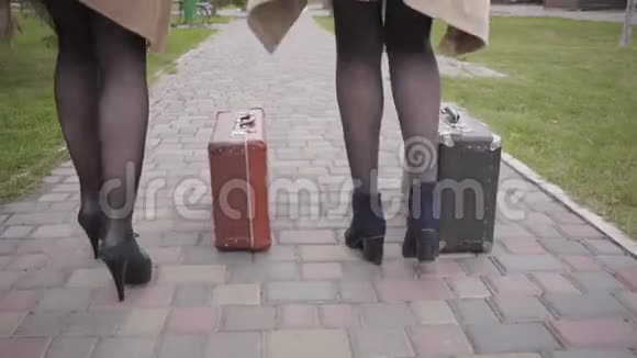 两个女人穿着高跟鞋带着旧的旅行袋走开优雅的女性朋友视频的预览图