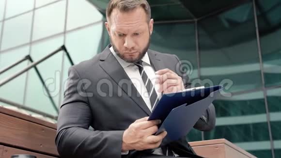 一个商人在纸上做笔记和喝咖啡的肖像视频的预览图
