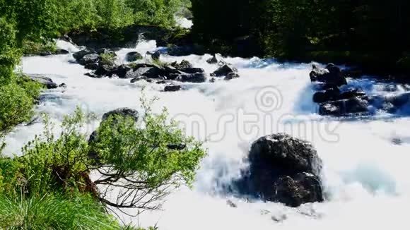 关闭一段湍急的白水从挪威山上融化的雪中迅速流过美丽的岩石河视频的预览图