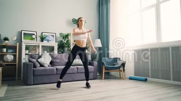 女孩在家练习蹲着举起手臂在客厅锻炼视频的预览图