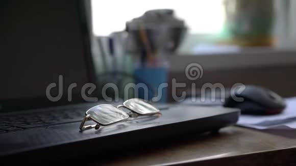 眼镜躺在现代笔记本电脑上站在家里的桌面上视频的预览图