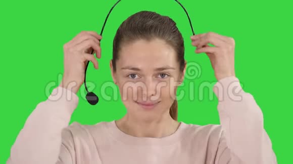 漂亮的女性支持中心操作员与耳机微笑相机上的绿色屏幕色度键视频的预览图