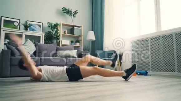 活跃的男人在家锻炼躺在地板上锻炼腿和手臂视频的预览图