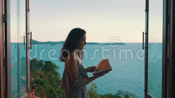 女孩在海洋的背景下翻阅一本书视频的预览图