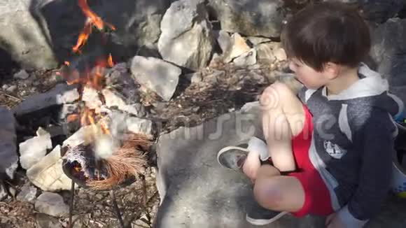 小孩坐在石头上生火视频的预览图