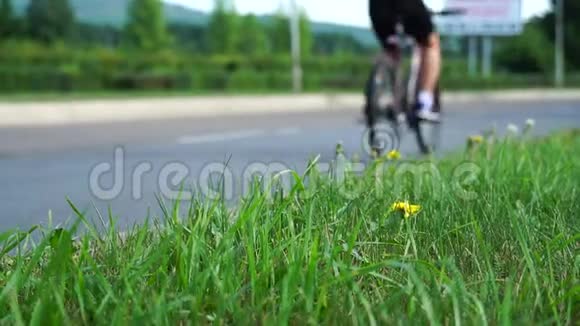 汽车骑自行车的人在路上背景模糊特写镜头聚焦在前景的草地上视频的预览图