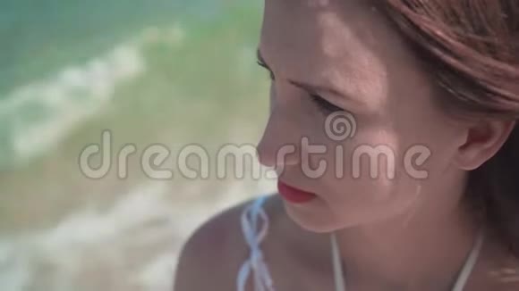 一个穿着白色裙子的女孩在海滨的肖像美丽的女孩嘴唇涂着红色的口红头发在风中发展视频的预览图