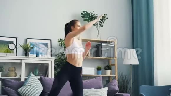穿运动服装的苗条女人在家锻炼举起手臂和蹲下视频的预览图