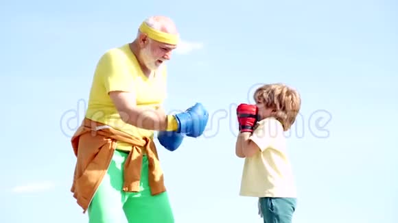 英俊的老人练习拳击健康战士祖父和带拳击手套的孙子祖父视频的预览图