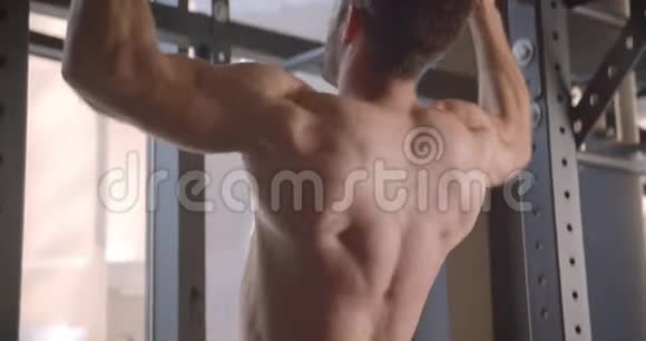 在健身房里一个穿着衬衫肌肉发达的白种人在酒吧里站起来的特写后景视频的预览图