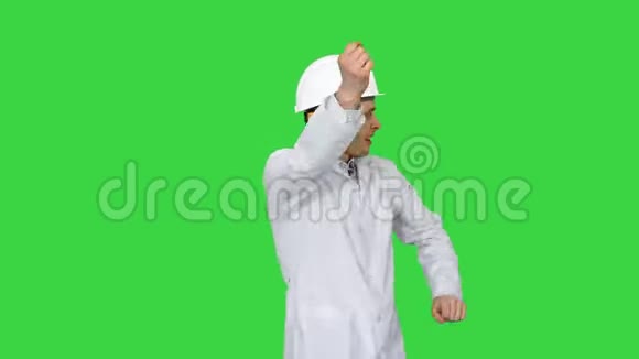 年轻的工人戴着白色长袍的头盔喜欢在绿色屏幕上跳舞Chroma键视频的预览图