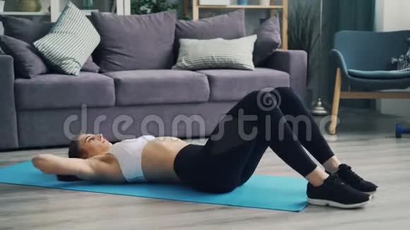 肌肉发达的年轻女士在家里练习瑜伽垫上的腹部肌肉视频的预览图