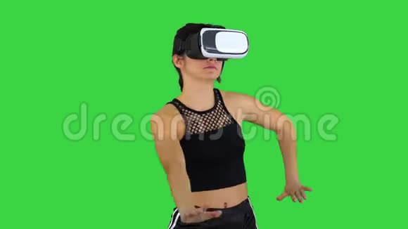 快乐微笑的年轻女孩使用VR耳机眼镜玩舞蹈游戏第一次在绿色屏幕Chroma键视频的预览图