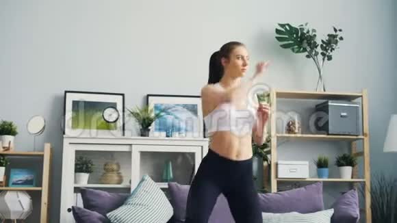 漂亮的年轻女运动员在家里练习举起手臂独自蹲着视频的预览图