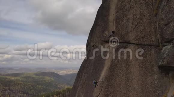 两个人爬上一堵垂直的岩石墙登山伙伴保险视频的预览图