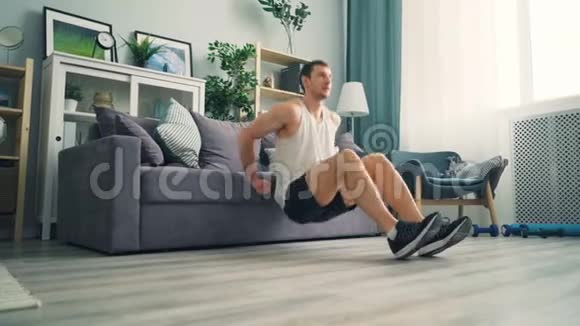 肌肉男在家里用沙发做手臂肌肉的俯卧撑练习视频的预览图