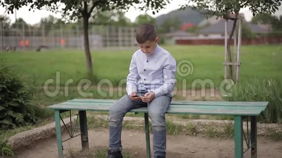 放学后坐在长凳上玩网络游戏的帅哥视频的预览图