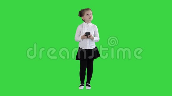 可爱的小女孩在智能手机上看并在绿色屏幕上写一条信息Chroma键视频的预览图
