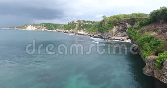 巴厘岛的海岸有巨大的岩石和高大的悬崖热带岛屿波浪状的海洋4k视频的预览图