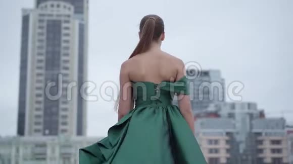 美丽美丽美丽的女孩穿着一件漂亮的晚绿色连衣裙迷人地走在附近空荡荡的城市广场上视频的预览图
