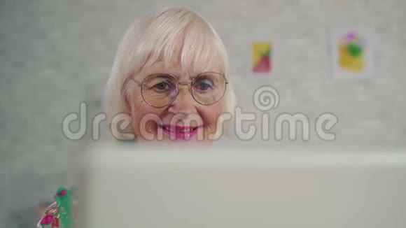 一位老年妇女坐在客厅里的时候使用笔记本电脑视频的预览图