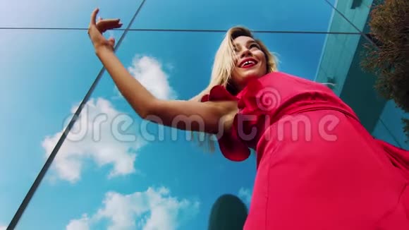 穿红色连衣裙的性感女士在室外对着镜面跳舞的低角度镜头视频的预览图