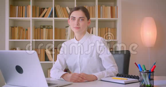 年轻漂亮的白种人女商人的特写镜头她看着镜头开心地坐在镜头前视频的预览图