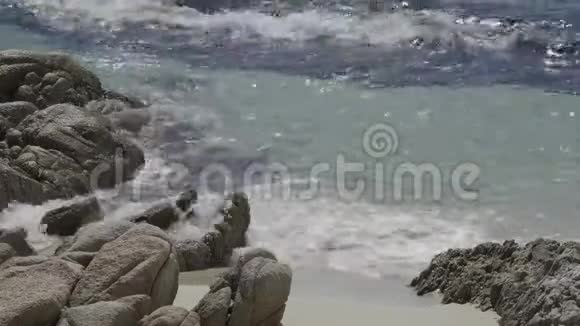 靠近海浪在海滩上的岩石与阳光闪烁的光反射视频的预览图