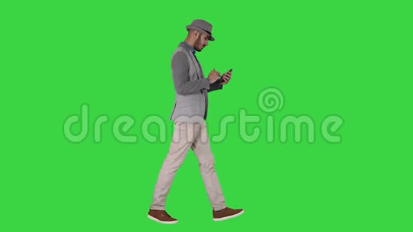 严肃的阿拉伯休闲男子使用智能手机同时行走在绿色屏幕Chroma键视频的预览图