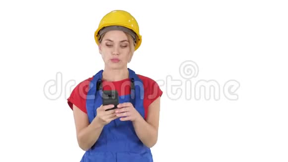 年轻的职业女性承包商戴着硬帽子在白色背景上用手机发短信视频的预览图