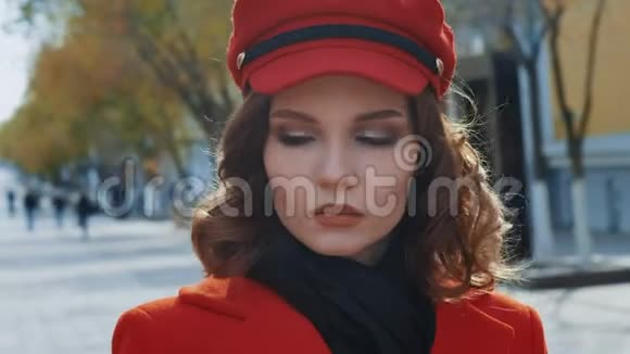 肖像年轻优雅的少女模特在秋天的城市拍照穿着红色外套看电影视频的预览图