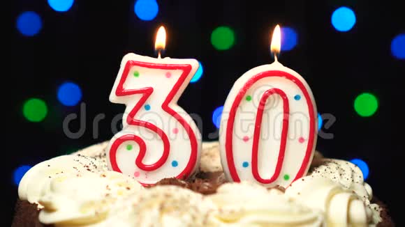 在蛋糕上面的30号30岁生日蜡烛燃烧在最后吹灭彩色模糊背景视频的预览图