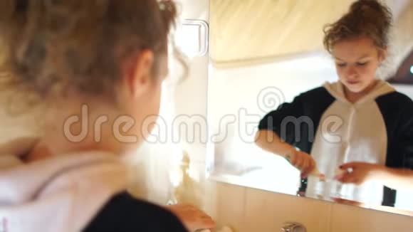 卷发少女正在镜子对面的浴室里刷牙晨间卫生良好习惯视频的预览图