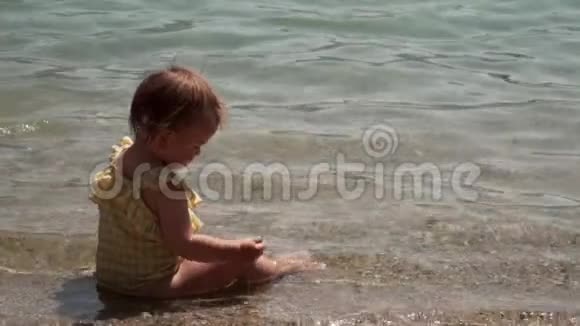 黄泳衣中的小女孩在水中嬉戏夏日与幼儿在海滩上的生活方式视频的预览图