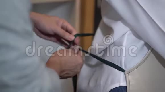 一个亚洲人把围裙系在女朋友身上准备一起做饭视频的预览图