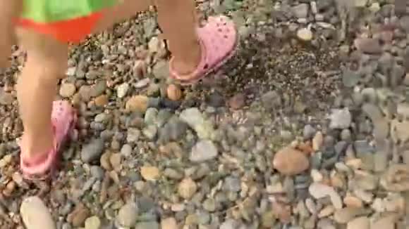 一个穿珊瑚拖鞋的小女孩在海滩上的岩石上视频的预览图