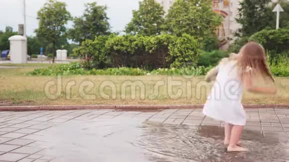 快乐的小女孩穿着白色裙子在水坑里跳舞视频的预览图